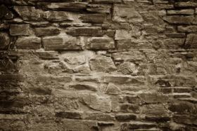 old stone brick wall background in sepia