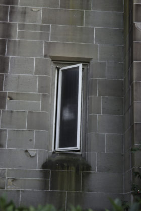 a small window in the grey brick wall
