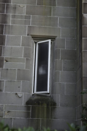 a small window in the grey brick wall