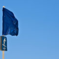blue flag on the beach with arrow to show surfing area