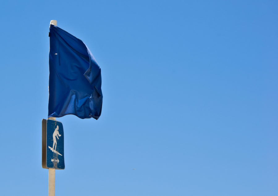 Stock photo of a blue flag on the beach with arrow to show surfing area