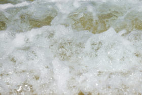 Closeup photo of the foam of a small beach wave